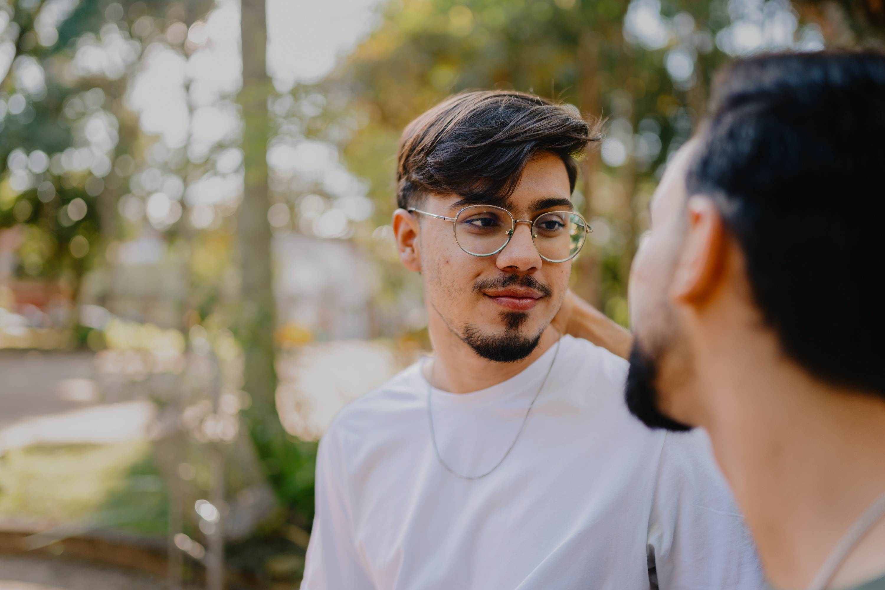 Two Latine men, embracing and smiling in a park